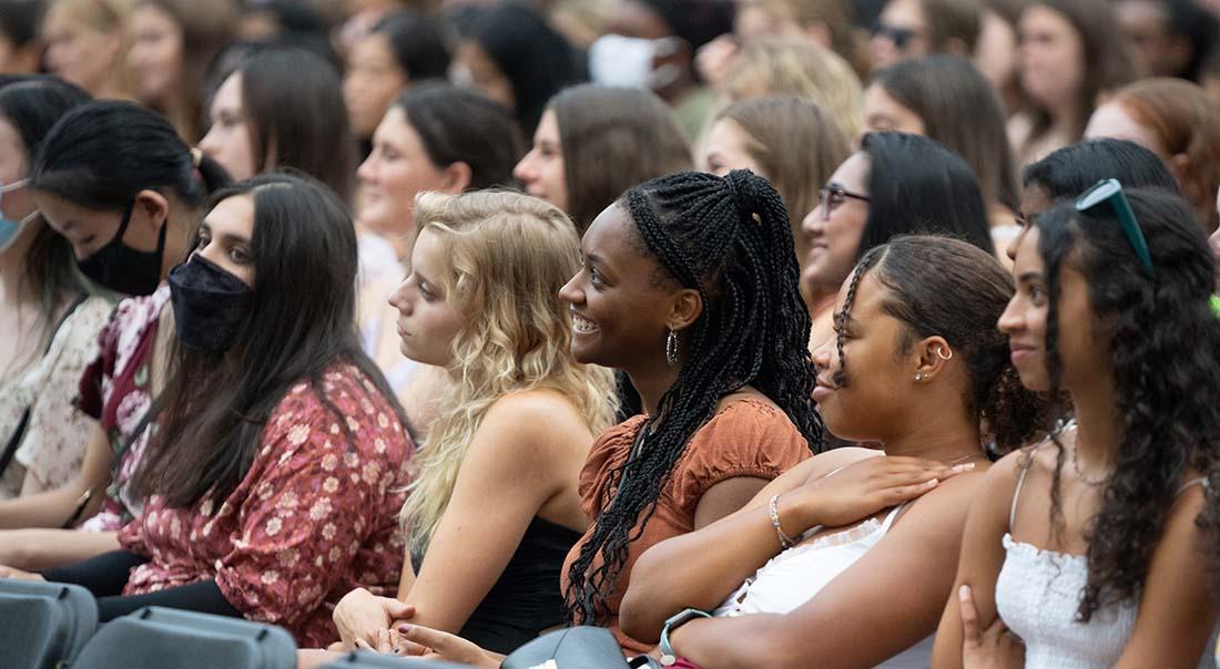 Diverse group of smiling female students sitting in a crowd